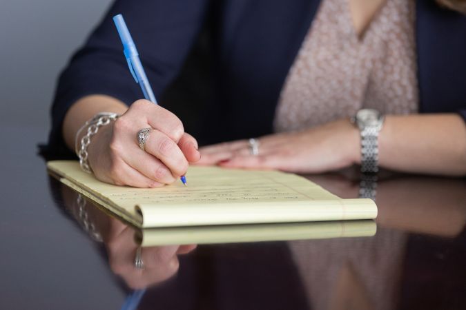 woman writing on legal pad - Family Lawyers discuss who gets the family pet after divorce - Feinman & Childs Family Law