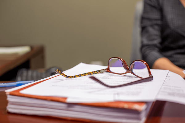 glasses on top of papers and book | Vetrano Vetrano & Feinman